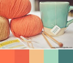 a coffee cup with yarn and knitting needles in it next to a mug filled with oranges