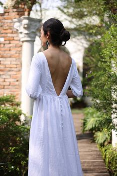 a woman in a white dress walking down a path