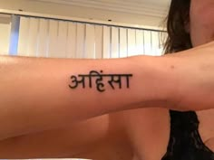 a woman with a tattoo on her arm that reads, in the language of yoga