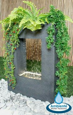 an outdoor fountain with plants growing on the sides and water running down it's side