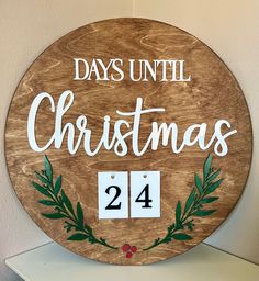 a wooden sign that says days until christmas 24 and has green leaves around the numbers