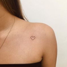 a woman with a small heart tattoo on her chest