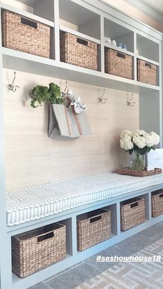 a white bench with baskets and flowers on the wall next to it in a room