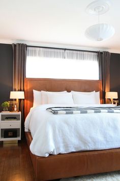 a bed with white sheets and pillows in a bedroom next to two lamps on either side of the bed