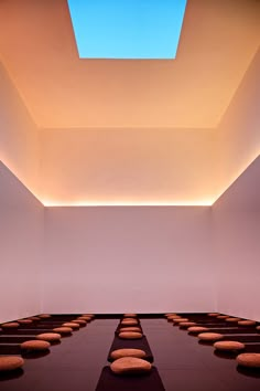 an empty room with benches and skylight in the ceiling is lit by lights from above