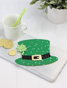 a st patrick's day hat and coins on a tray next to a mug