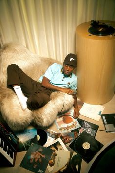 a man sitting on top of a couch covered in records