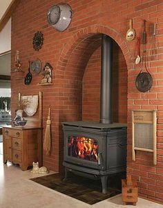 a wood burning stove sitting inside of a living room next to a wall with pots and pans on it