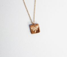 Introducing the Square Dragonfly Necklace, a delicate and meaningful piece designed for those who embrace the beauty of simplicity. Choose between the timeless elegance of sterling silver or the warm radiance of 14k gold-filled, each capturing the essence of this charming accessory.The 8mm dragonfly charm, hand-stamped with care, adds a touch of whimsy to this dainty necklace. Its petite size makes it an ideal everyday piece, perfect for those who appreciate subtle yet striking jewelry.Embrace v Square Necklace, Dragonfly Charm, Dragonfly Necklace, Heartfelt Gifts, Dainty Necklace, Timeless Pieces, Hand Stamped, Timeless Elegance, Gold Filled