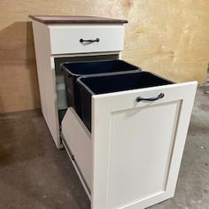 a white cabinet with two black bins on top and one blue bin in the bottom