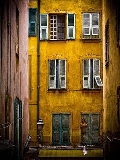 an alleyway with several windows and shutters on the side of each building in europe