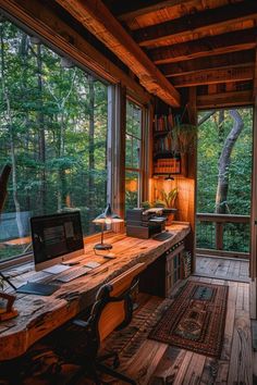 a computer desk sitting on top of a wooden table in front of a large window