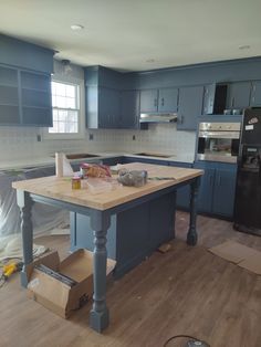 the kitchen is being remodeled with blue cabinets and wood flooring, including an island