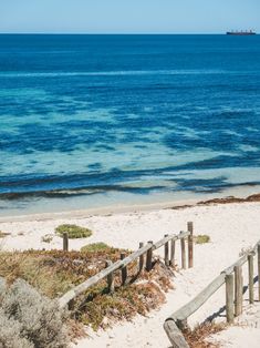 an ocean view with blue water and wooden steps leading up to the sand beach area