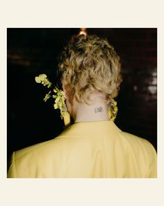 the back of a woman's neck with flowers in her hair and words on it