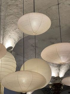 several white lamps hanging from the ceiling in a room with concrete walls and ceilings,