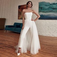 a woman standing in a room wearing a white dress