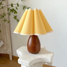 a lamp that is sitting on top of a white table next to a potted plant