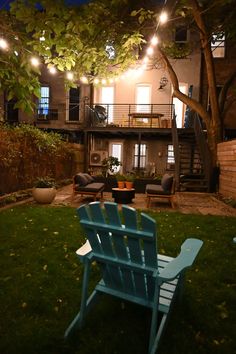 a blue chair sitting on top of a lush green field next to a building at night