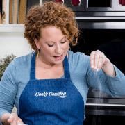 a woman wearing an apron is cooking in the kitchen with her hands on a plate