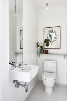 a white bathroom with a sink, toilet and mirror