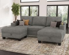 a living room with a gray sectional couch and lots of pillows on top of it