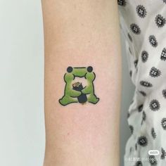 a small tattoo on the arm of a woman with a green dog bone in it