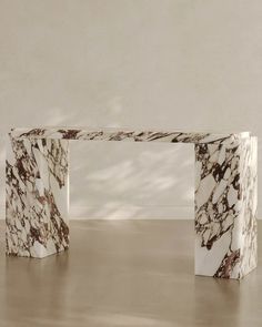 a marbled bench sitting on top of a wooden floor next to a white wall