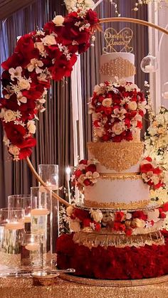 a three tiered wedding cake with red and white flowers on the top is surrounded by candles