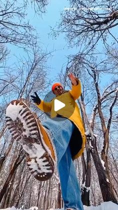 a man riding a snowboard down a snow covered slope in front of some trees