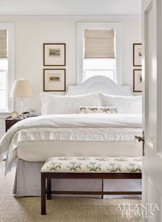 a white bed sitting in a bedroom next to two windows