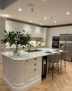 a large kitchen with white cabinets and marble counter tops