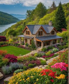 a beautiful house surrounded by flowers and greenery on the side of a mountain with a lake in the background