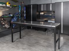 a kitchen with gray cabinets and black counter tops is shown in this image, there are many tools on the table