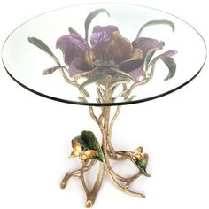 a glass and metal table with flowers on the top, sitting against a white background