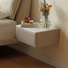 a small table with flowers on it next to a bed