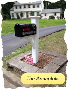 a mailbox sitting on the side of a road in front of a white house