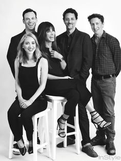 a group of people sitting on top of a white stool next to each other in black and white