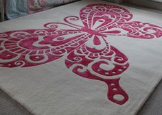 a pink and white rug with an intricate design on the floor in front of a window