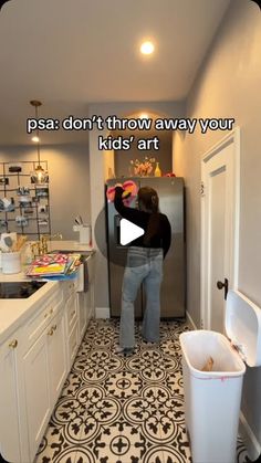 a person standing in front of a refrigerator next to a trash can and a sink