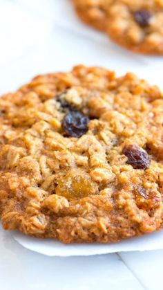 two oatmeal raisin cookies sitting on top of a white paper plate