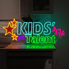 a neon sign that says kids's got talent next to a computer keyboard and mouse