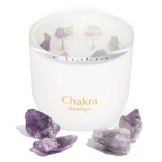 an amethyst crystal candle with the words chakra on it next to some rocks