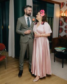 a man standing next to a woman in a pink dress