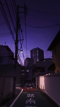 an empty street with power lines and buildings in the background at night, tokyo, japan