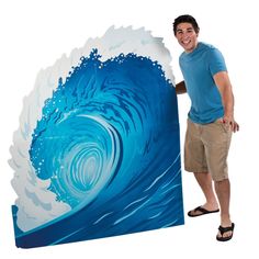 a man standing next to a large blue and white wave painting on the wall in front of him