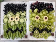 two trays filled with grapes, cucumbers and blackberries in the shape of faces