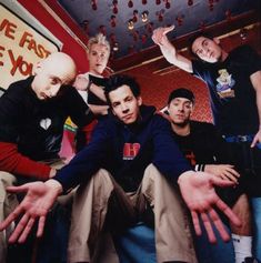 a group of young men sitting next to each other in front of a red wall