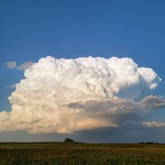 a large cloud looms over an open field