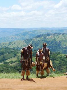 three men in native garb standing on a hill